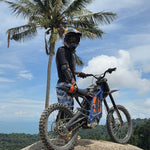 Electric Dirt Bike Tour 3 Hours Koh Samui – rider and electric dirt bike under a palm tree at a viewpoint – TourInKohSamui.com