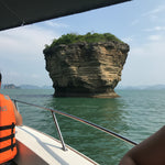 Private speedboat anchored beside the layered Pancake Rock formation on the Khanom coast