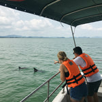 Guests scanning the open water from a private speedboat while searching for wild pink dolphins off Khanom