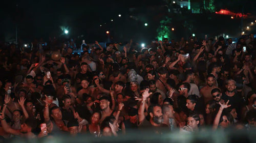 Utopia Party Koh Phangan – huge crowd dancing with hands in the air under red stage lights