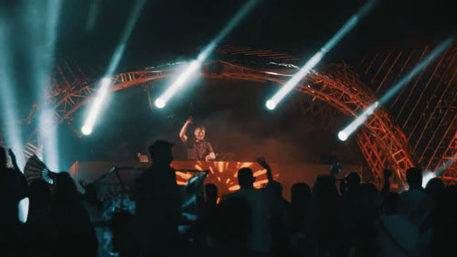 Utopia Party Koh Phangan – DJ booth under an orange arch structure with white laser beams